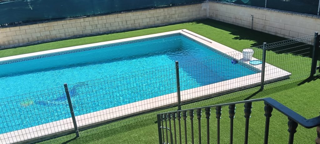 Césped artificial instalado junto a piscina con vallado de seguridad - Limcesped Sevilla